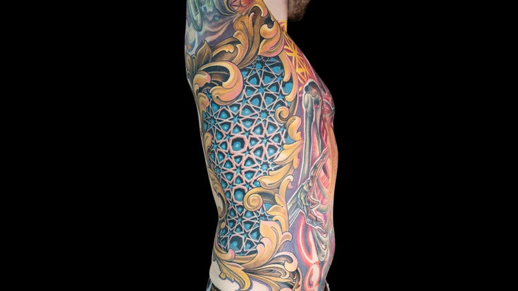 Detailed color tattoo of ornamental scrollwork and a geometric star pattern along a client's side and ribs