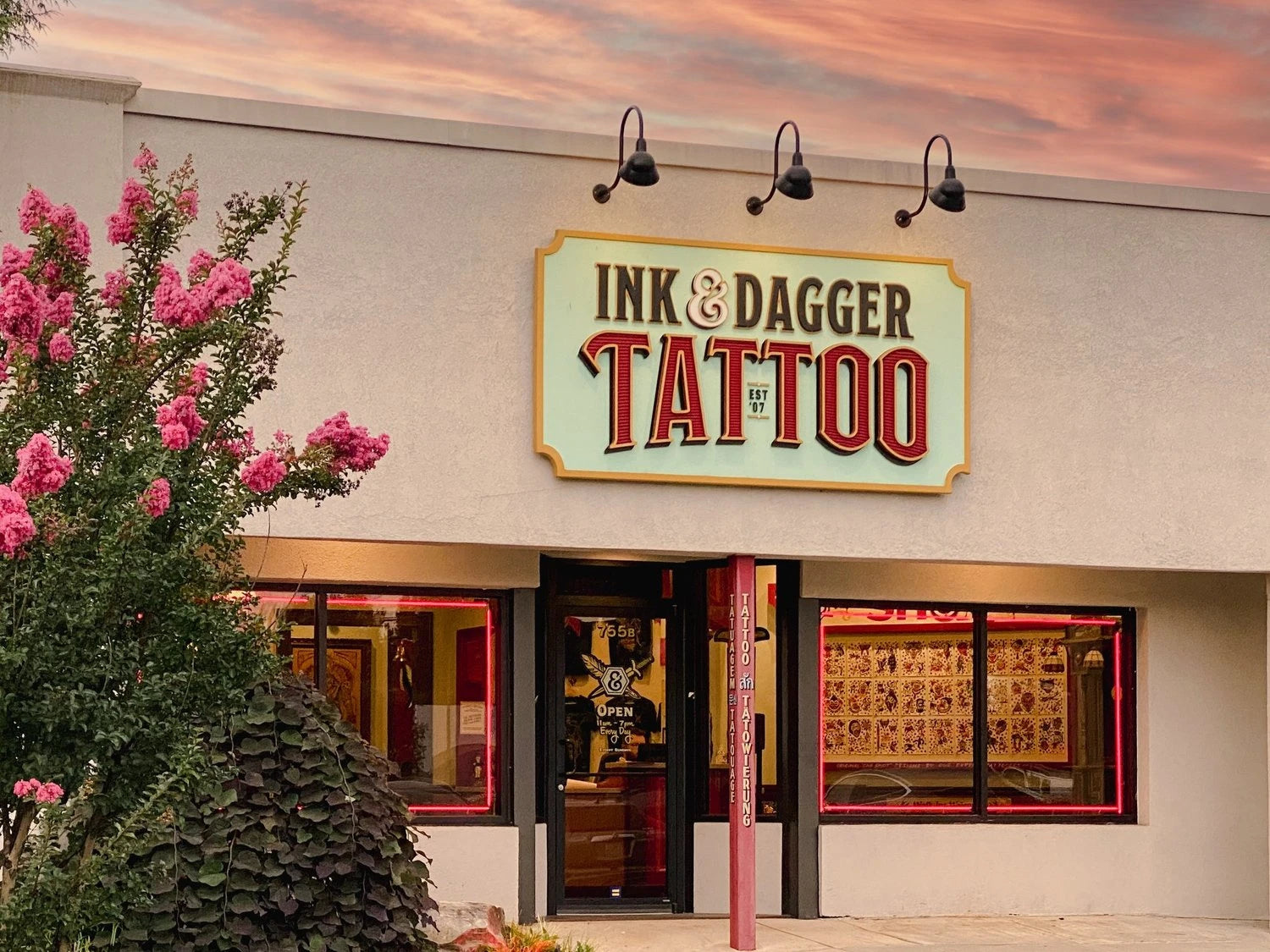 Exterior of the Ink & Dagger Tattoo storefront at dusk with the illuminated sign, used as the site's social share preview image
